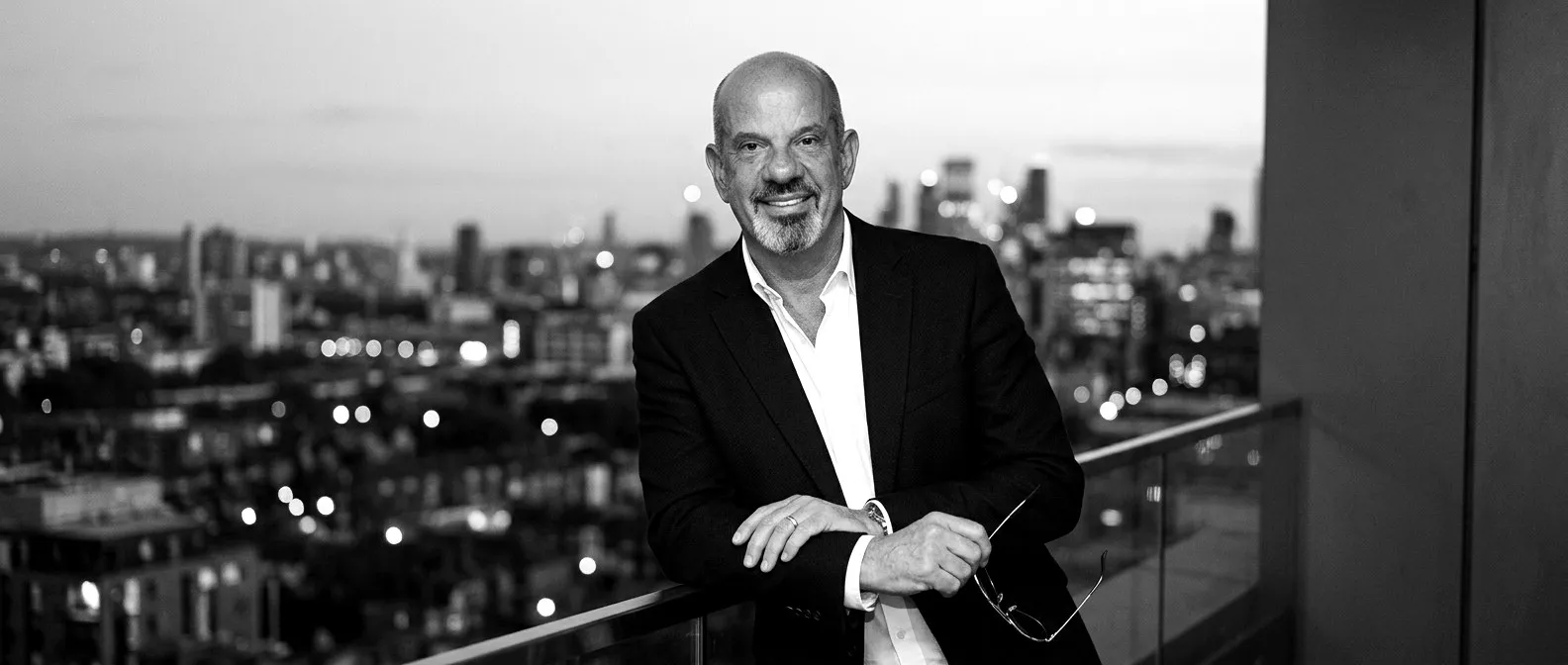 Graham Tennant on a rooftop terrace at dusk with the London skyline behind him
